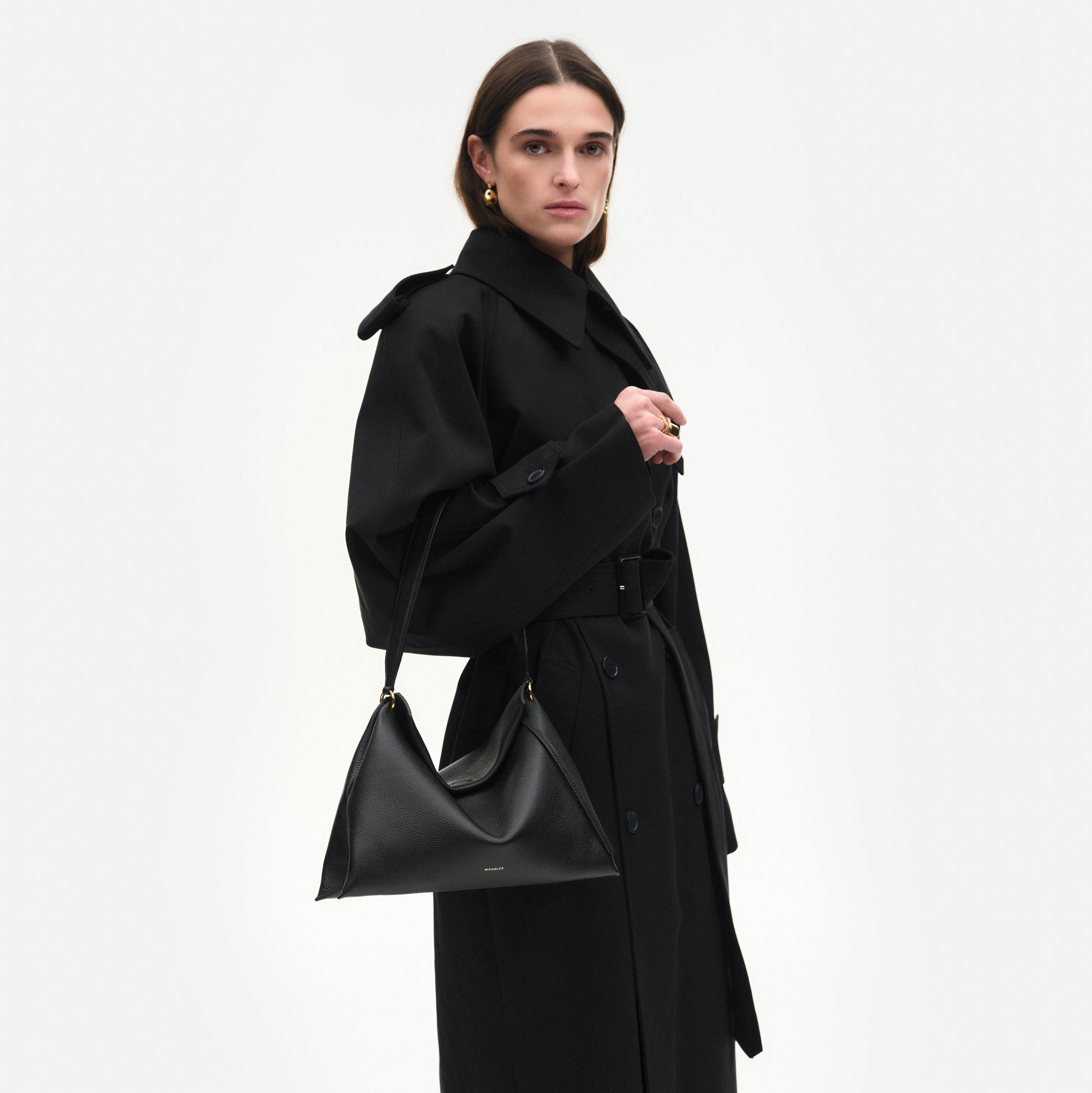 Wandler Penelope Tote Small in the color Black Crust made from calf leather with golden hardware and soft slouchy silhouette, pictured being worn on the fore arm by model, half body picture.